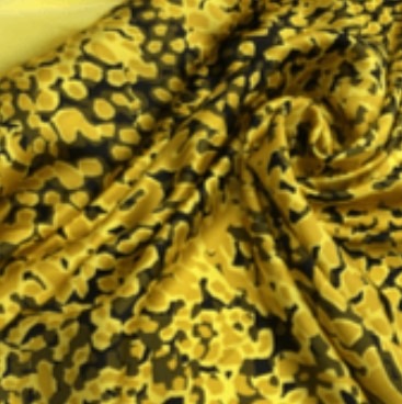 Żółto-czarna tkanina z abstrakcyjnym wzorem, ułożona w miękkie fałdy, ukazująca fakturę materiału.