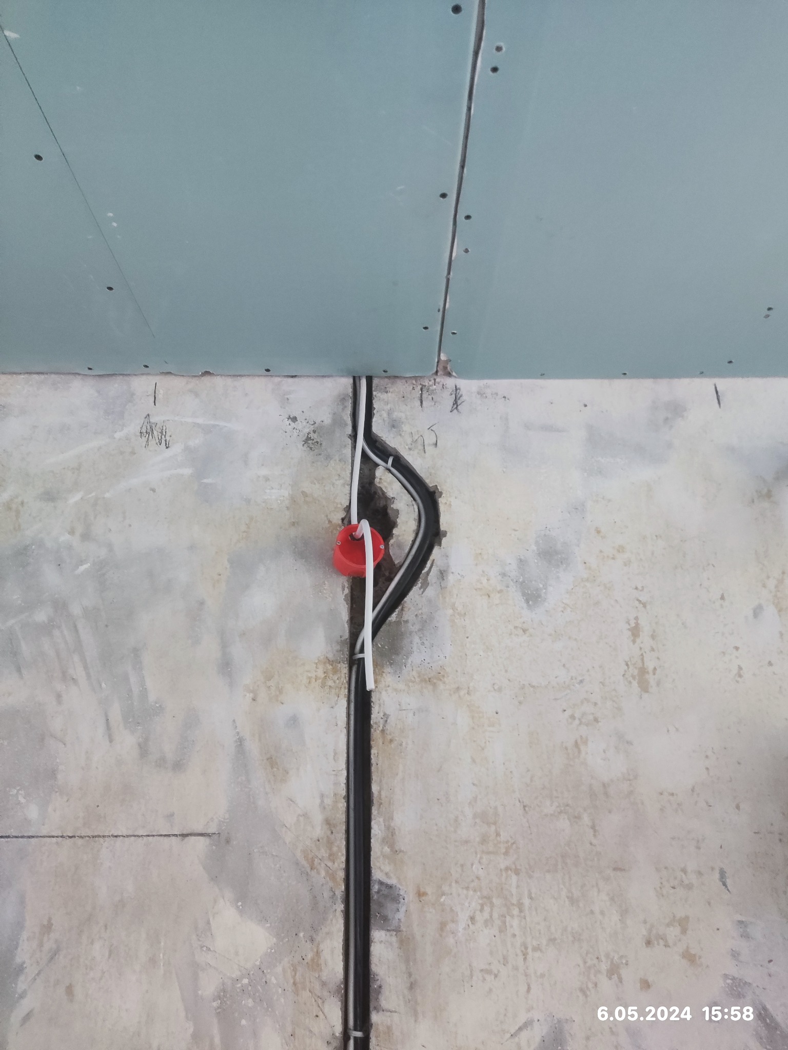 Instalacja elektryczna w ścianie z widoczną puszką instalacyjną i przewodami w peszlu, przed wykończeniem ściany płytą gipsową.