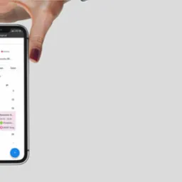 Dłoń trzyma smartfon z widocznym kalendarzem rezerwacji online, prawdopodobnie systemu rezerwacji usług oferowanego w Szczytnie.