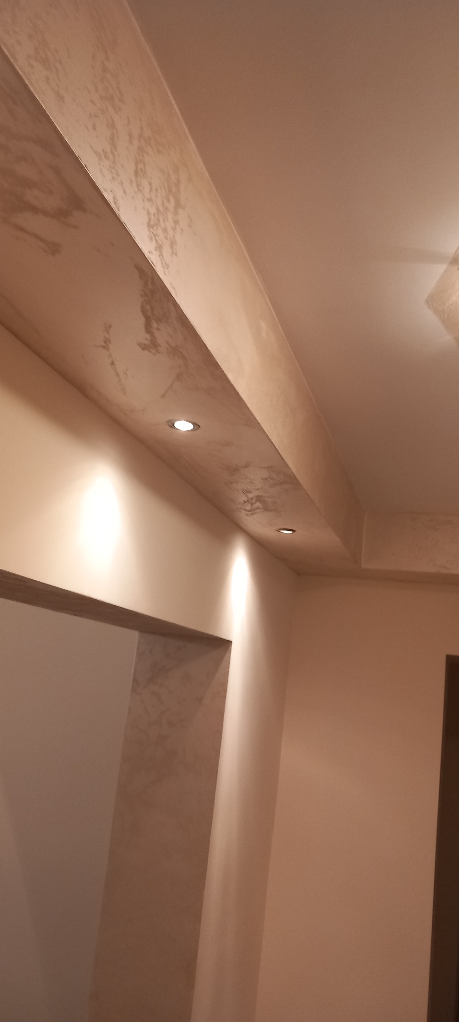 Beżowe wnętrze z wykończonym sufitem i ścianami, dekoracyjna faktura gładzi na suficie podwieszanym z wbudowanymi punktowymi lampami LED.