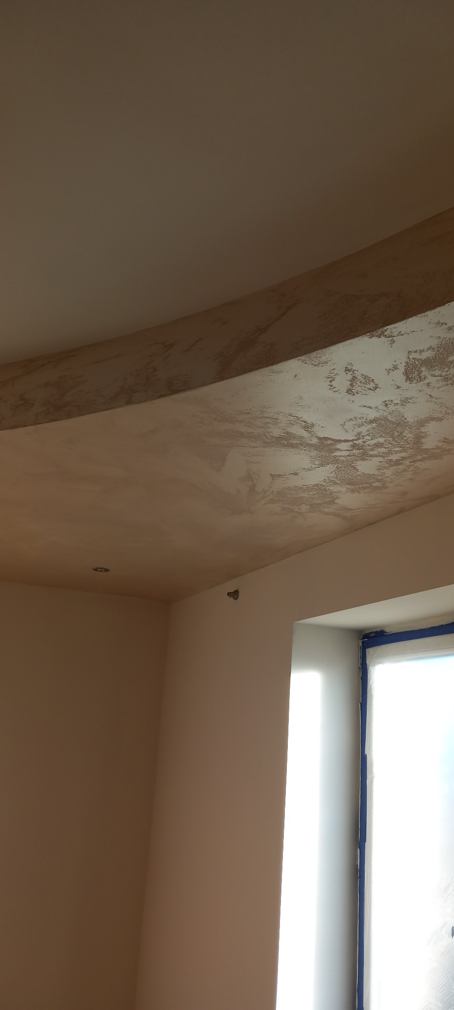 Ściana i sufit po nałożeniu gładzi, widoczna faktura i przygotowanie do malowania, okno zabezpieczone folią.