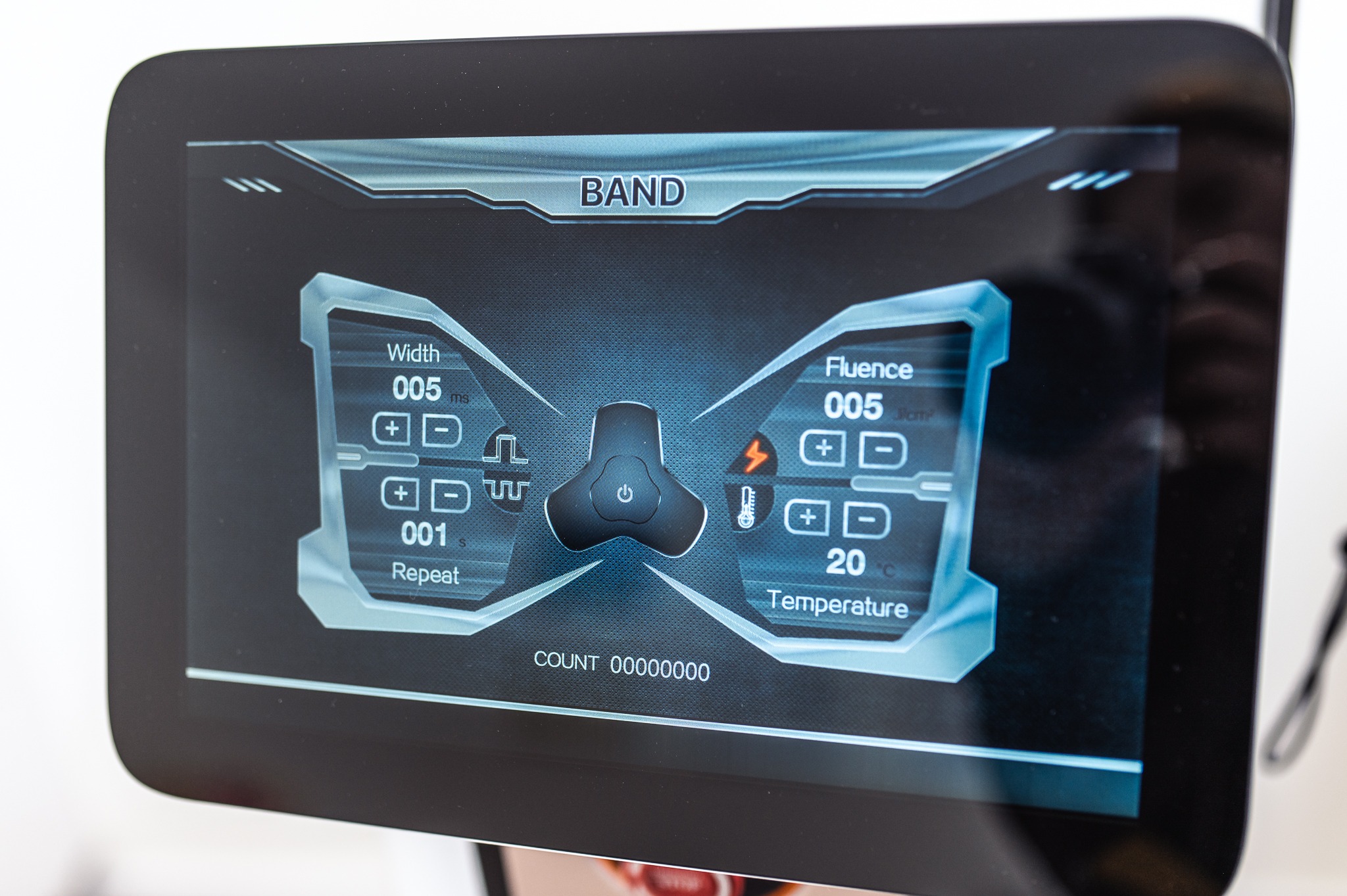 Ekran dotykowy urządzenia kosmetycznego z ustawieniami: szerokość impulsu 005 ms, powtórzenie 001 s, fluencja 005 j/cm², temperatura 20°C, oraz licznik wykonanych zabiegów: 00000000.