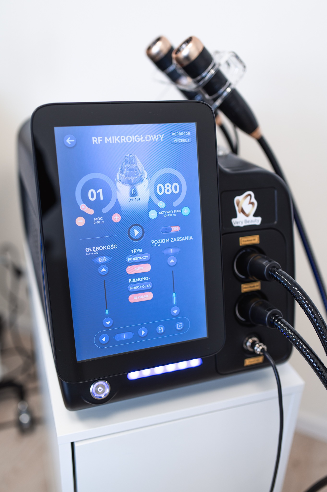 Urządzenie do RF mikroigłowej w salonie w Malborku, z widocznym ekranem dotykowym i głowicami zabiegowymi, ustawione na białej szafce.