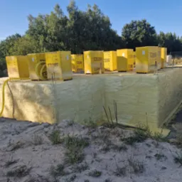 Fundament budynku w Gorzowie Wielkopolskim po izolacji, pokryty warstwą pianki, z paletami bloczków Ytong na górze, widoczne elementy instalacji.
