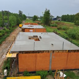 KRIS-bud ROBERT SERVACHAK - Wylane fundamenty pod budowę domów jednorodzinnych z czerwonej cegły, widok z góry na kilka budynków w trakcie realizacji, szalunki i mokry beton.