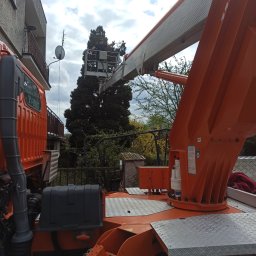 P.H . I U.E. ELBART Bartosz Lewandowski - Prace elektryczne wykonywane z podnośnika koszowego przy budynku mieszkalnym, widoczna antena satelitarna na balkonie.