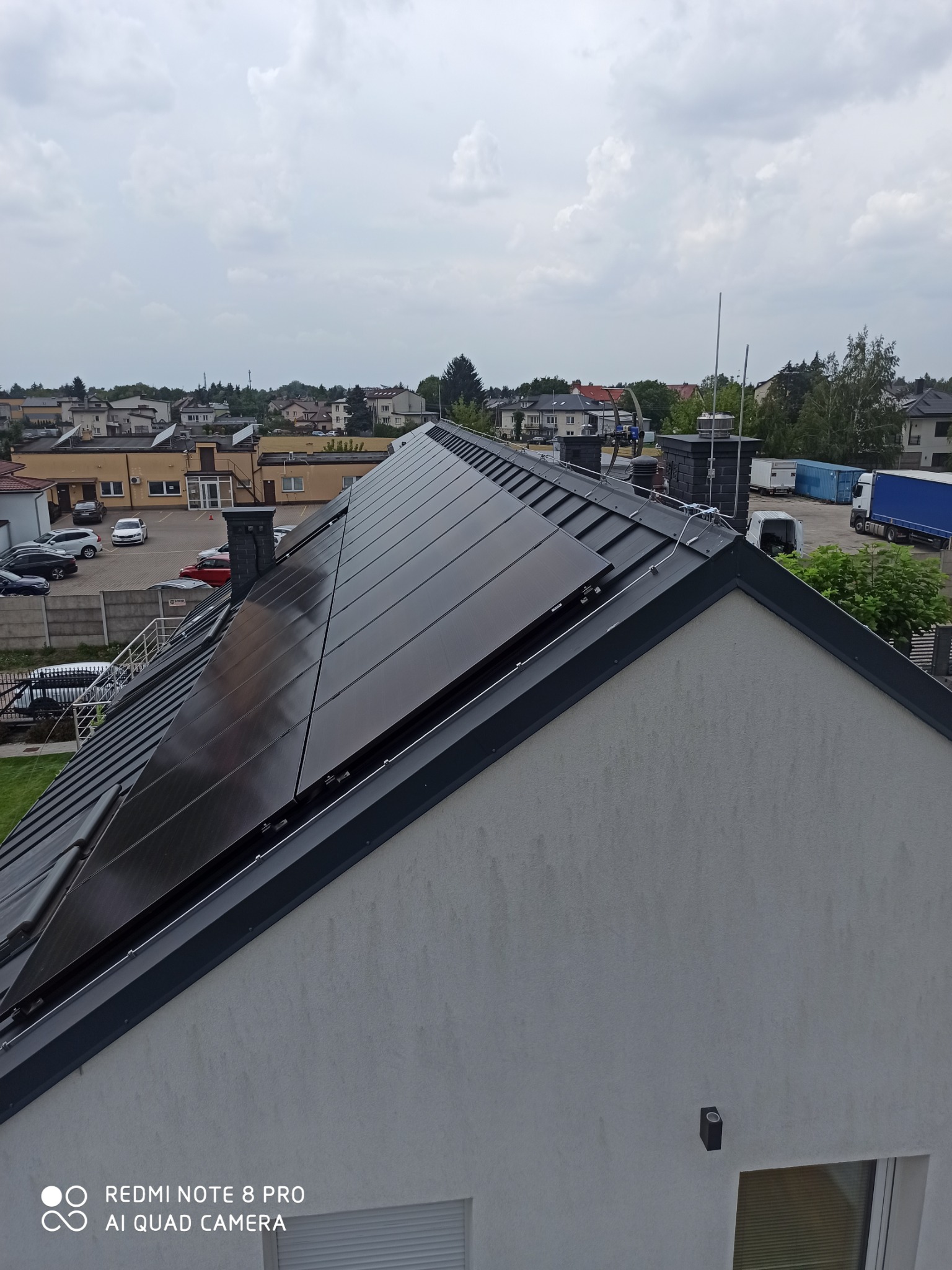 Widok z góry na dach domu w Mogielnicy z zainstalowanymi panelami fotowoltaicznymi i instalacją odgromową, widoczne przewody i uchwyty mocujące.