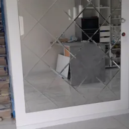 Dekoracyjne lustro ścienne z rombów w Stargardzie, odbijające wnętrze kuchni z wyspą i regałami, na tle marmurowej podłogi.