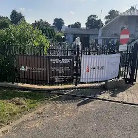 Ogrodzenie posesji z banerami reklamowymi firmy transportowej Albud Cargo, widoczne logo i dane kontaktowe.
