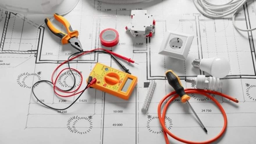 Narzędzia elektryczne, miernik, gniazdko, żarówki, przewody i schemat instalacji elektrycznej ułożone na białym tle.