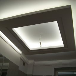 Dariusz Sadło - Sufit podwieszany z oświetleniem LED w kształcie kwadratu, widoczna wisząca żarówka na kablu, odbicie w lustrze.