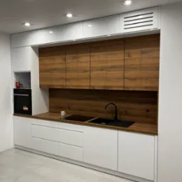 Nowoczesna kuchnia z białymi szafkami dolnymi i górnymi w kolorze drewna, czarny zlew i bateria, minimalistyczny design, oświetlenie punktowe sufitowe