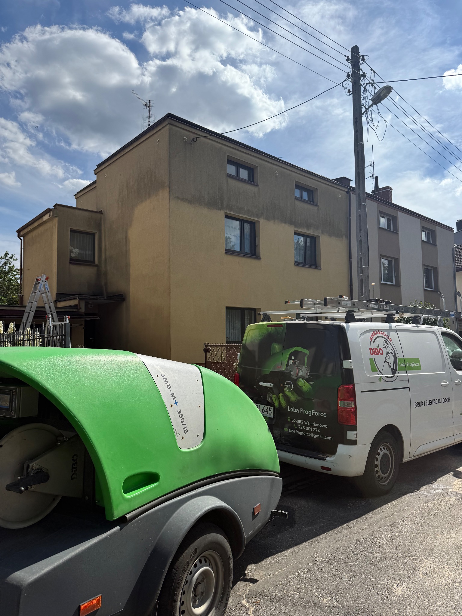 Budynek po częściowym myciu elewacji, z widocznymi pojazdami firmy Loba FrogForce i sprzętem DIBO. Drabina oparta o ścianę.