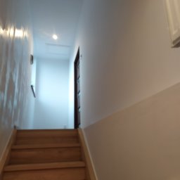 Bartosz Nowak - Schody drewniane prowadzące na poddasze w Pszowie, z widocznymi świeżo pomalowanymi ścianami w jasnym odcieniu.