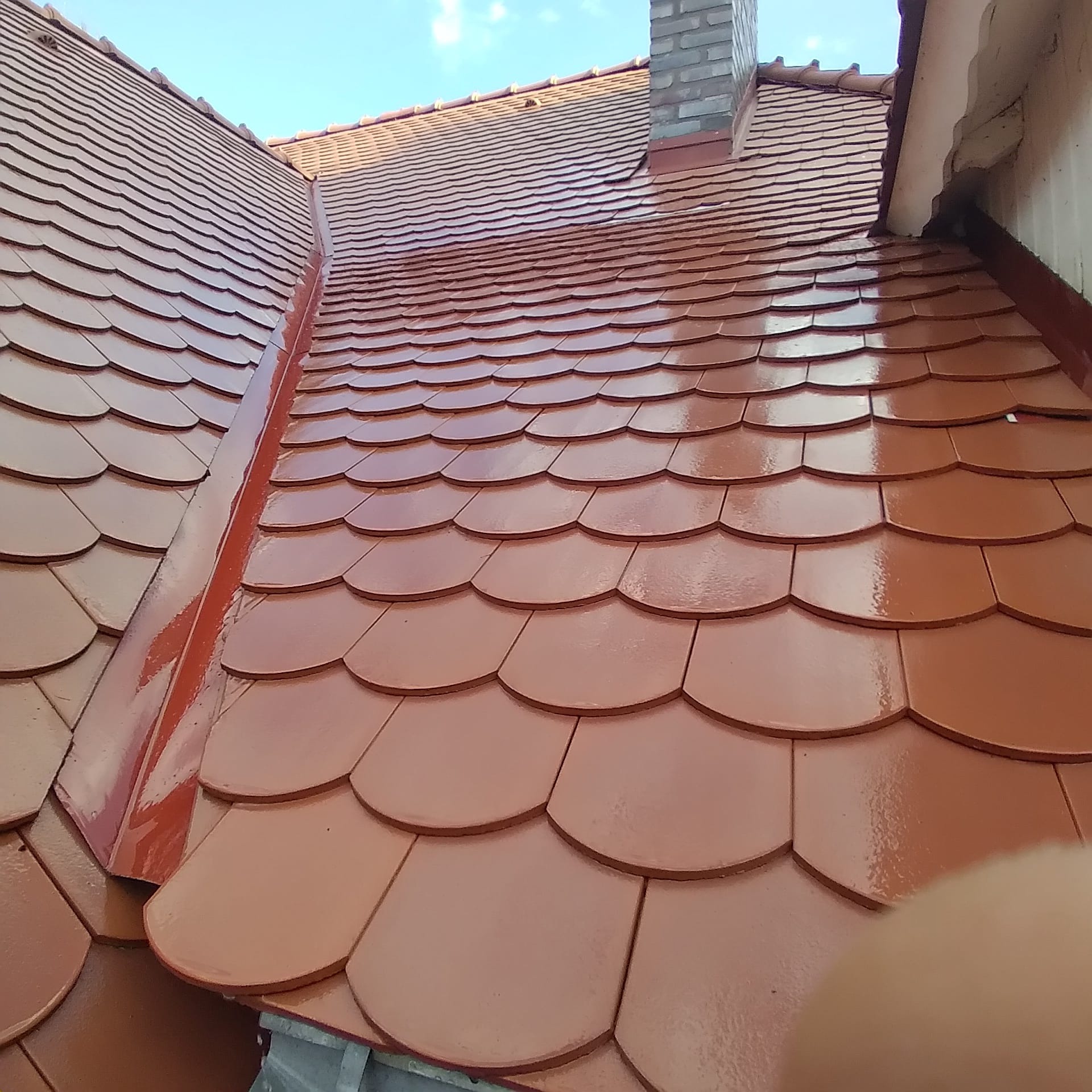 Odnowiony dach z dachówki karpiówki w Turku, z widocznym kominem i świeżo pomalowaną powierzchnią.