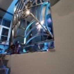 sebastian misiak - Nierdzewna balustrada o nowoczesnym, geometrycznym wzorze, wykonana w Łodzi. Widoczne spawy i odbicia światła na polerowanej powierzchni stali. Ujęcie od dołu, ukazujące fragment schodów.