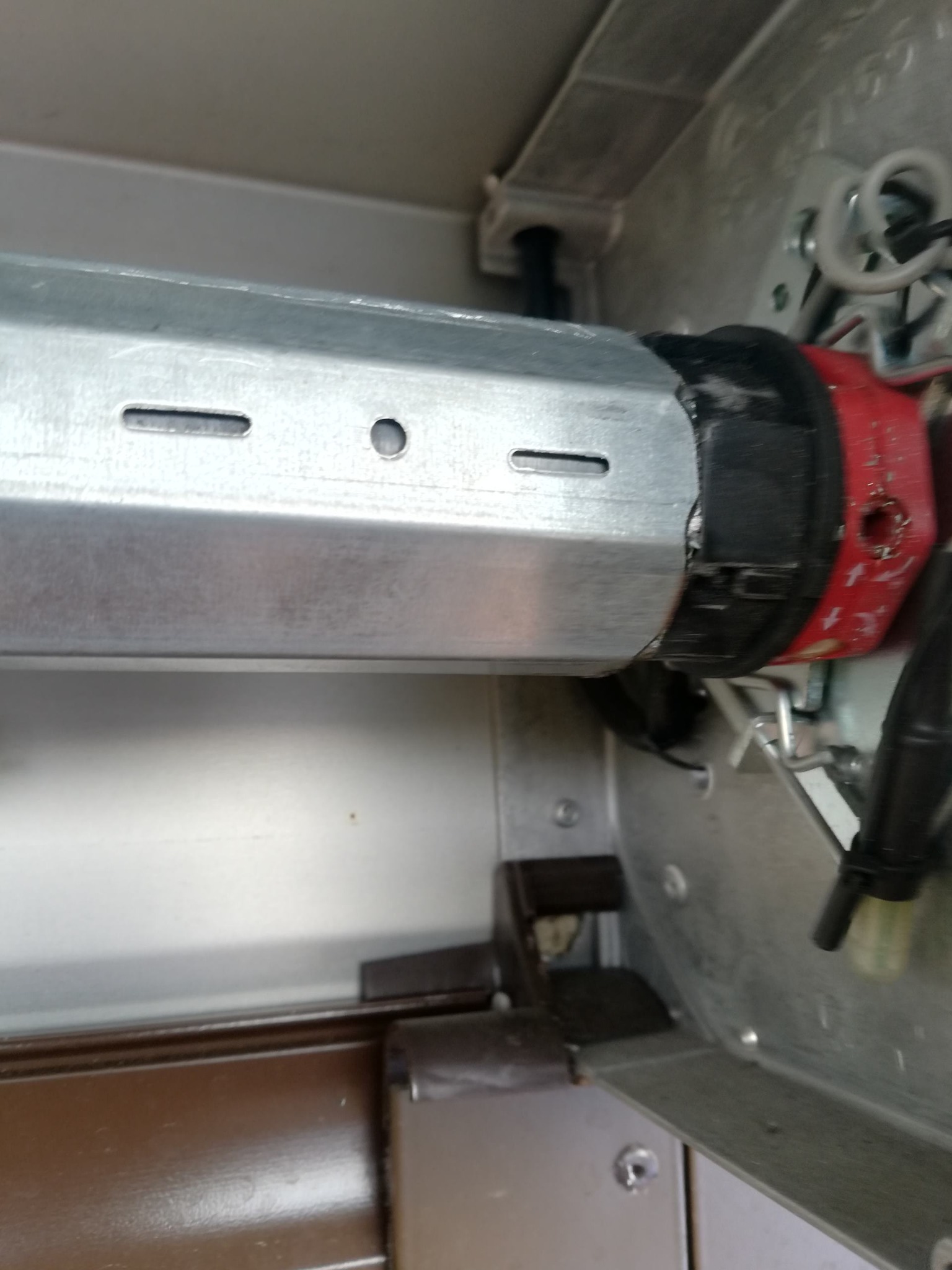 Wnętrze obudowy rolety zewnętrznej z widocznym mechanizmem zwijającym, silnikiem z czerwoną obudową i przewodami elektrycznymi.