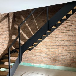 METAL-CHROM - Nowoczesne schody metalowe z drewnianymi stopniami na tle ściany z cegły, widoczne kable elektryczne i niedokończone wykończenie podłogi.