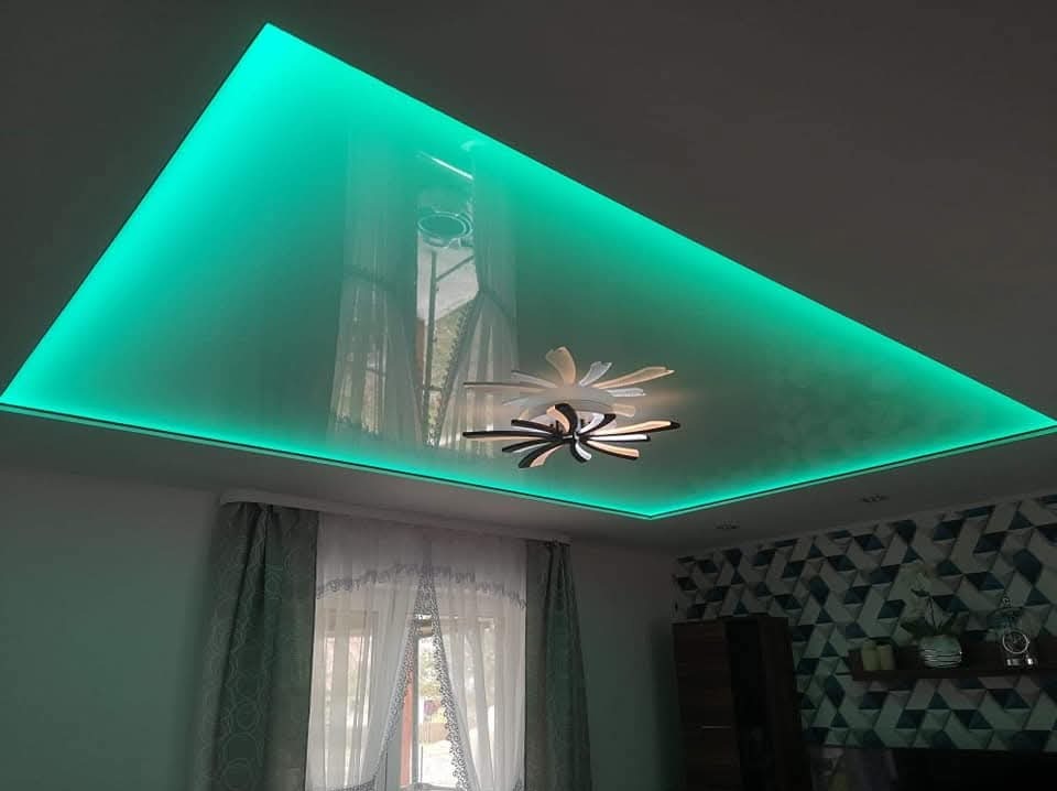 Podwieszany sufit z połyskiem i oświetleniem LED w kolorze turkusowym, nowoczesna lampa, wzorzysta tapeta w tle. Wykończenie wnętrza z dbałością o detale.