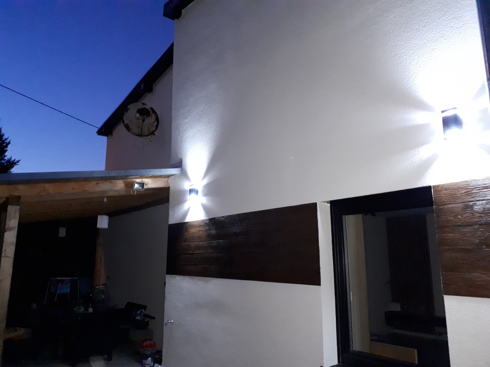 Elewacja budynku w Jeleniej Górze z oświetleniem zewnętrznym i dekoracyjnym panelem imitującym drewno, sfotografowana o zmierzchu.