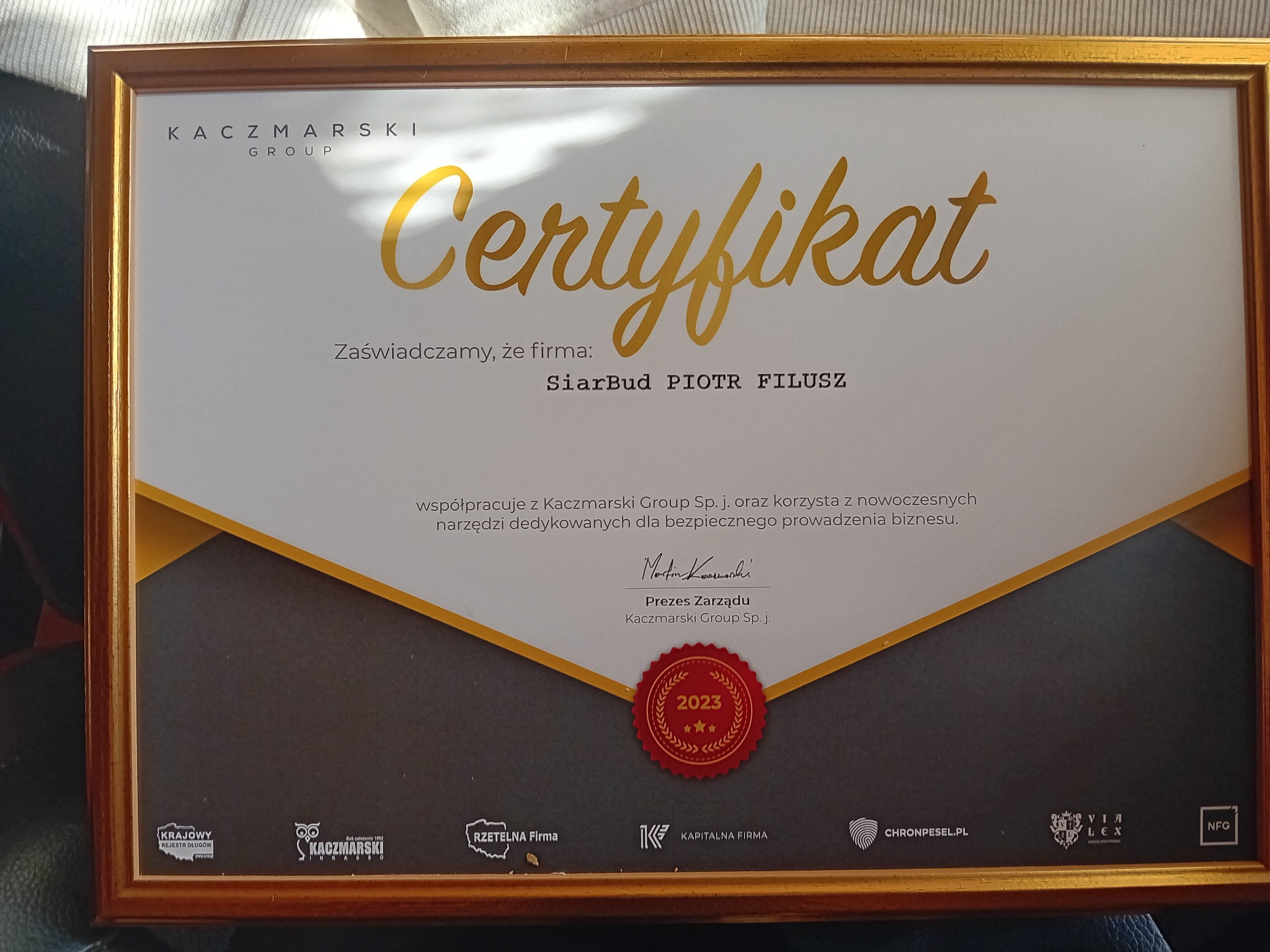 Złota ramka z certyfikatem firmy SiarBud PIOTR FILUSZ, potwierdzającym współpracę z Kaczmarski Group w 2023 roku.