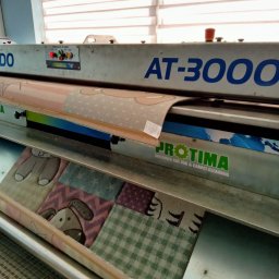 Perfekt Dywan - Automatyczna Pralnia Dywanów NATALIA NEUMANN - Automatyczna maszyna AT-3000 marki PROTIMA w trakcie czyszczenia dywanów, z widocznymi dywanami z dziecięcymi wzorami w środku.