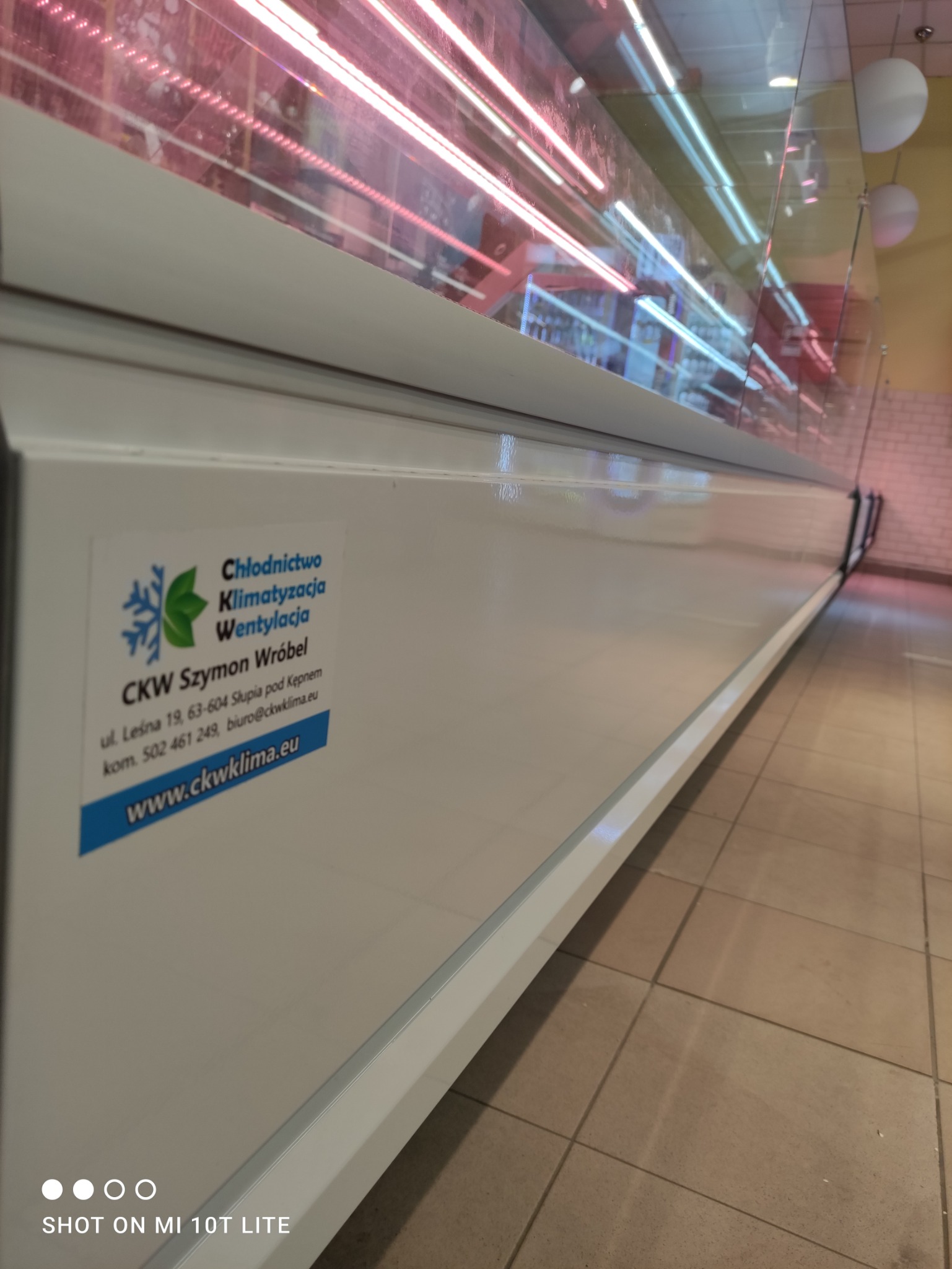 Biała obudowa lady chłodniczej z naklejoną reklamą firmy CKW Szymon Wróbel oferującej usługi chłodnictwa, klimatyzacji i wentylacji, z widocznym adresem strony internetowej.