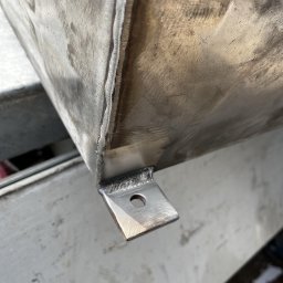 STAL-SPAW Karol Chwajoł - Fragment metalowej konstrukcji z widocznym spoiną i przymocowanym elementem mocującym z otworem, surowy wygląd metalu.