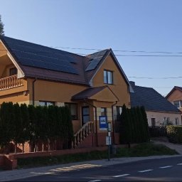 SABENERGY Sp. z O.O. - Dom jednorodzinny z panelami słonecznymi na dachu, widok z ulicy w słoneczny dzień.