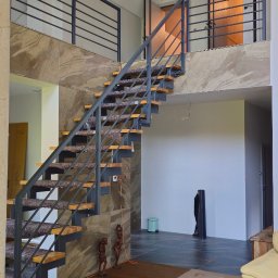 Alex Oleksandr Lisovyi - Dwupoziomowe wnętrze z nowoczesnymi schodami z metalową balustradą i drewnianymi stopniami z wykładziną, wykończone kamieniem dekoracyjnym, z widocznymi elementami zabezpieczającymi podłogę podczas...