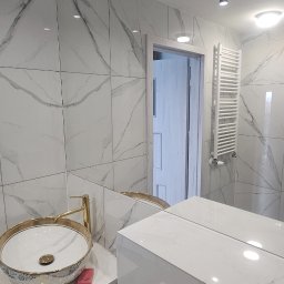 Alex Oleksandr Lisovyi - Nowoczesna łazienka z marmurowymi płytkami, ozdobną umywalką nablatową z elementami złota, chromowanym przyciskiem spłuczki, oraz podwieszanym grzejnikiem drabinkowym.