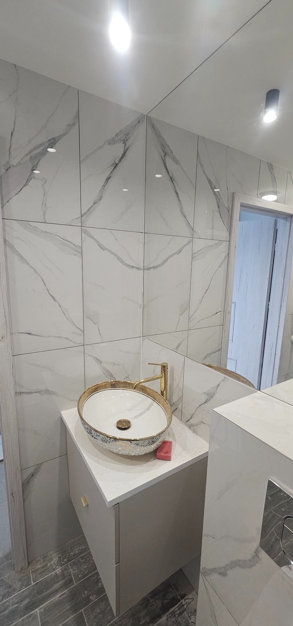 Umywalka nablatowa w stylu glamour z pozłacaną armaturą i marmurowymi płytkami w łazience po remoncie.