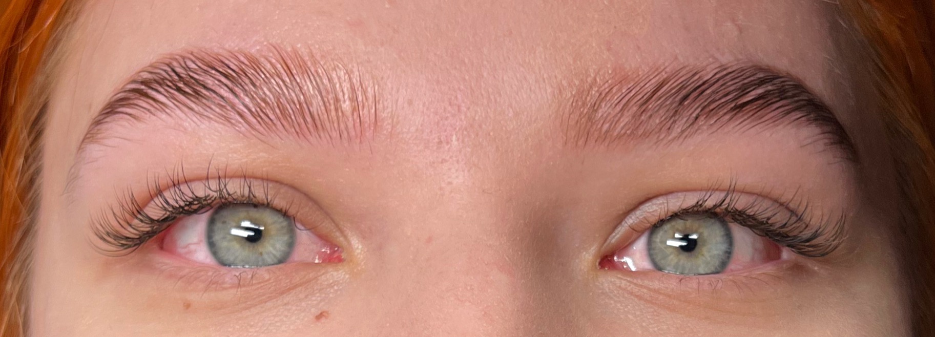 Zbliżenie na oczy z widocznymi, świeżo wystylizowanymi brwiami i przedłużonymi rzęsami; brwi są ciemne i błyszczące, a rzęsy długie i gęste.