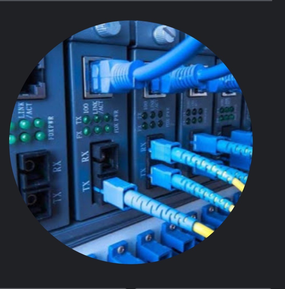 Szczegółowe ujęcie panelu krosowniczego z podłączonymi niebieskimi kablami światłowodowymi, widoczne diody LED sygnalizujące aktywność portów.