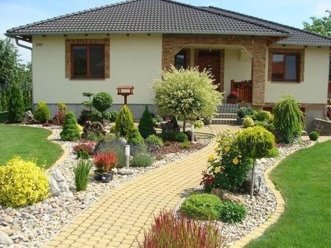 Starannie zaprojektowany ogród przed domem z krętą ścieżką z kostki brukowej, różnorodnymi krzewami ozdobnymi, drzewami formowanymi i trawnikiem, z karmnikiem dla ptaków po lewej stronie.