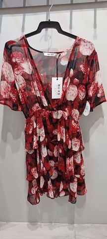 Sukienka mini z falbanami i wzorem w czerwone i białe kwiaty, wisząca na wieszaku, widoczna metka marki NA-KD.