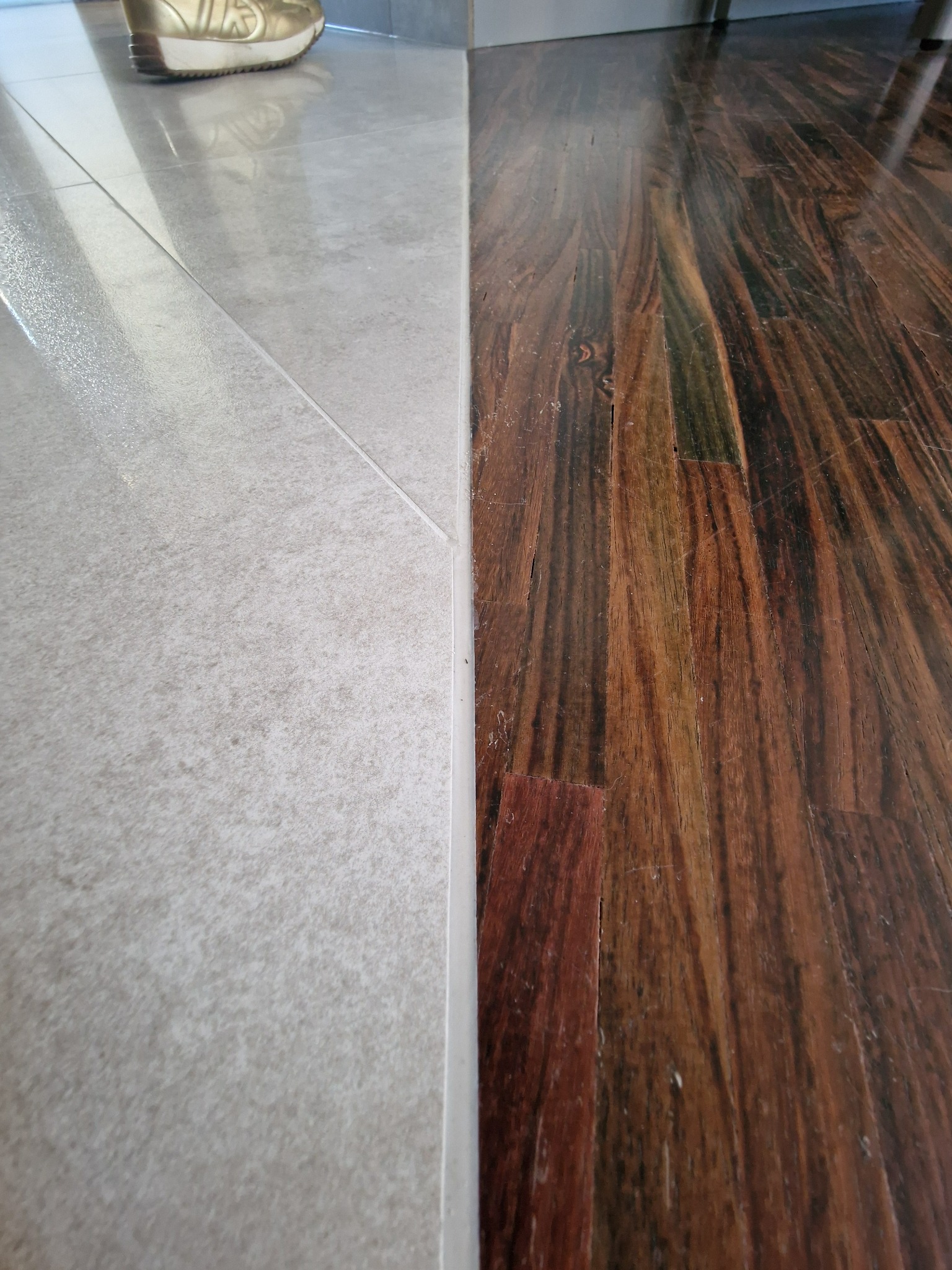 Wycięcie części podłogi drewnianej, położenie gresu oraz wykonanie połączenia obu części podłogi za pomocą sylikonu.