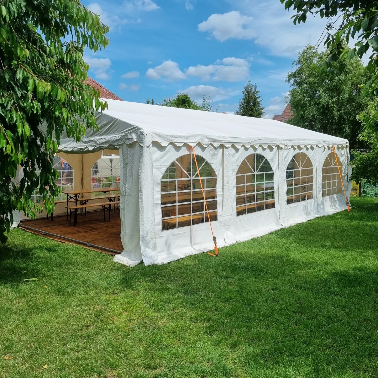 Biały namiot imprezowy 5x8m z drewnianą podłogą i widocznymi stołami wewnątrz, rozstawiony na trawniku w słoneczny dzień.