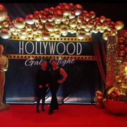 Daria Centka Jendrzej - Dekoracja imprezy w stylu Hollywood: złote balony, statuetka Oscara, czerwony dywan i osoby pozujące na tle scenografii 'Hollywood Gala Night'.