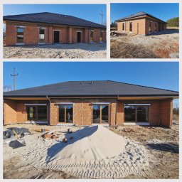 Montaż Partner - Surowy stan budynku jednorodzinnego z zamontowanymi oknami i drzwiami balkonowymi, widoczny stos piasku i materiały budowlane.