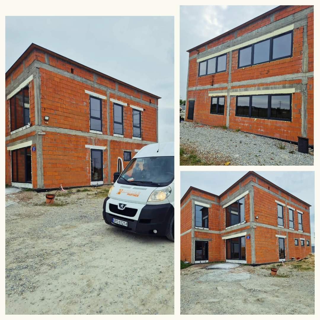 Nowo wybudowany dwupiętrowy budynek z czerwonej cegły z zamontowanymi czarnymi oknami, widoczny biały samochód dostawczy z logo firmy na podjeździe.