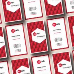 Układ wizytówek firmy M3 net z czerwono-białym geometrycznym tłem i danymi kontaktowymi Pawła Zębisza, Opiekuna Klienta.