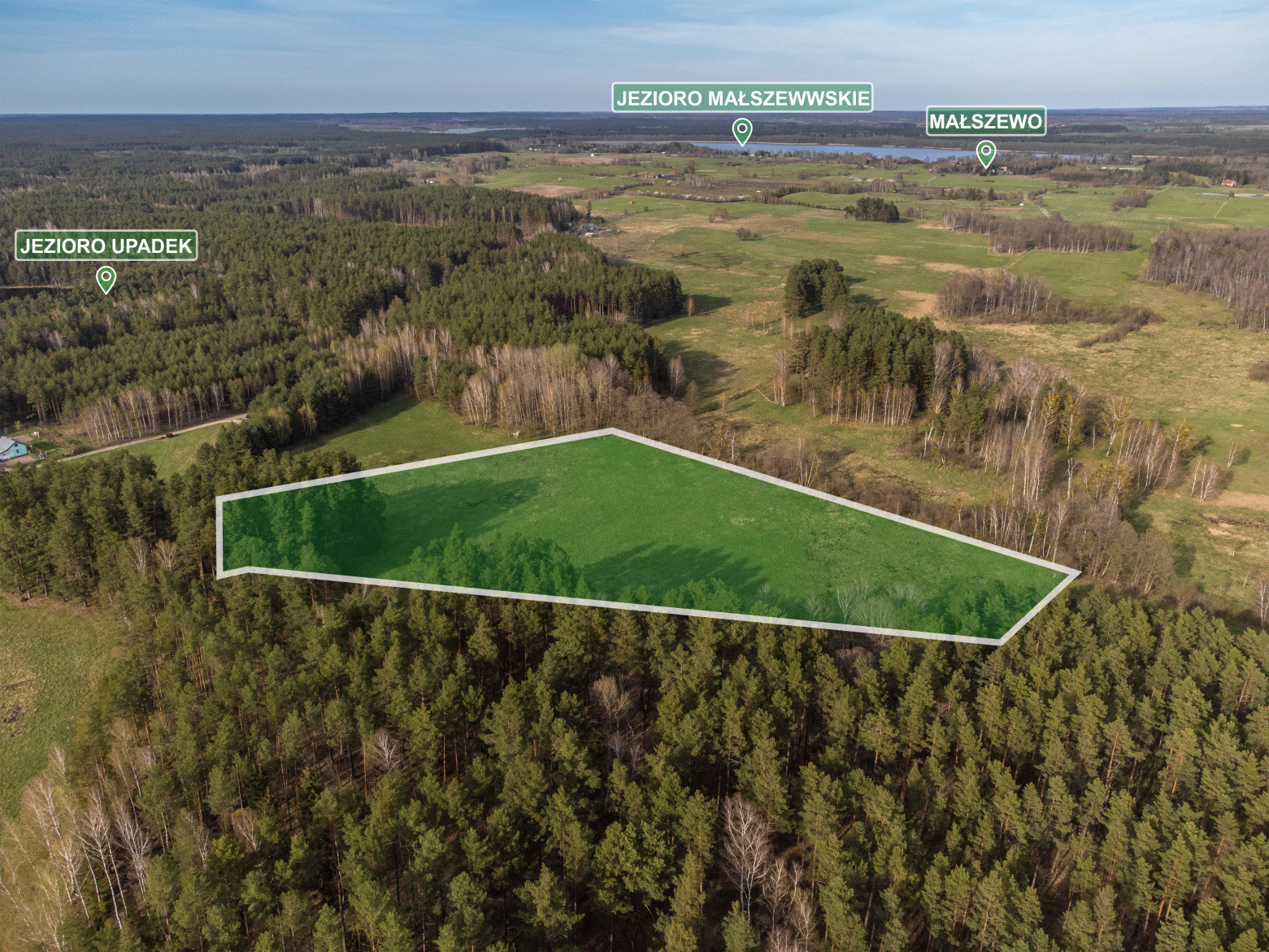 Widok z lotu ptaka na działkę z zaznaczonymi granicami na tle lasu i jezior Małszewskie i Upadek w tle.