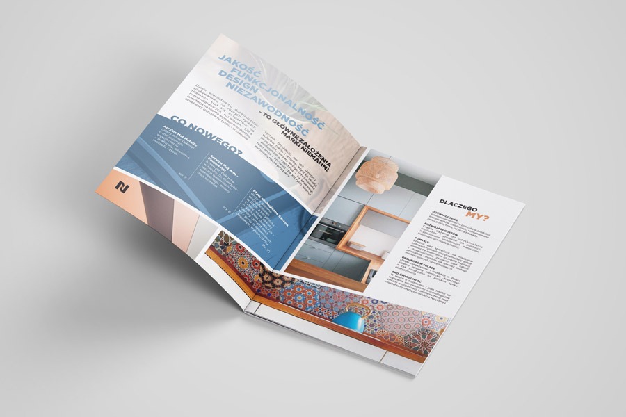 Rozłożona trójdzielna ulotka reklamowa prezentująca wnętrza z elementami dekoracyjnymi, leżąca na jasnoszarym tle, z widocznymi tekstami i grafikami.