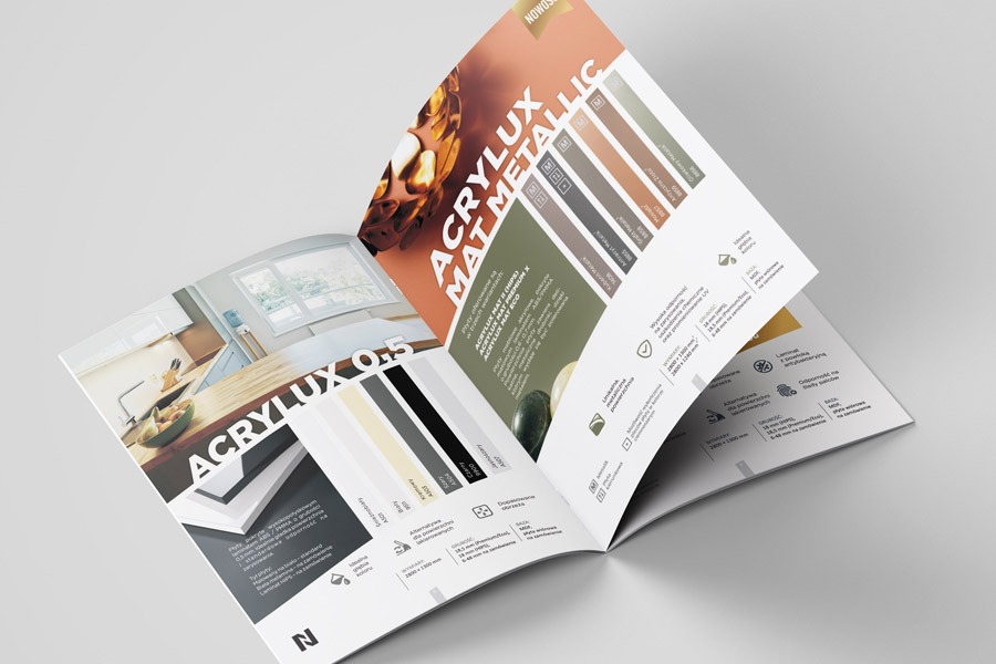 Otwarty katalog prezentujący paletę kolorów i wzorów paneli ściennych Acrylux, z widoczną aranżacją kuchni w tle.