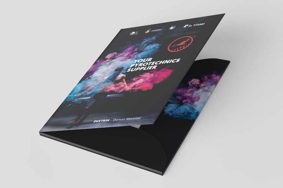 Czarna teczka firmowa z okładką przedstawiającą osobę w chmurze kolorowych dymów i logo firmy DEXTRIN, leżąca na szarym tle.
