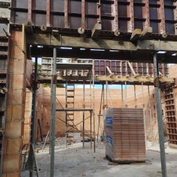 R-C BUD Robert Czuj - Budowa domu z pustaków ceramicznych: widoczne szalunki, rusztowania i paleta pustaków Leier na placu budowy.