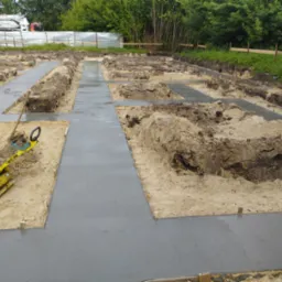 Wylane fundamenty pod dom w Radomyślu nad Sanem, widoczny ubijak wibracyjny i wykopane rowy.