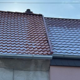 METAL-TRANS Mariusz Błoński - Fragment dachu z dwoma rodzajami dachówki: nową, czerwoną i starszą, ciemniejszą, z widocznym systemem rynnowym i fragmentami elewacji budynku.