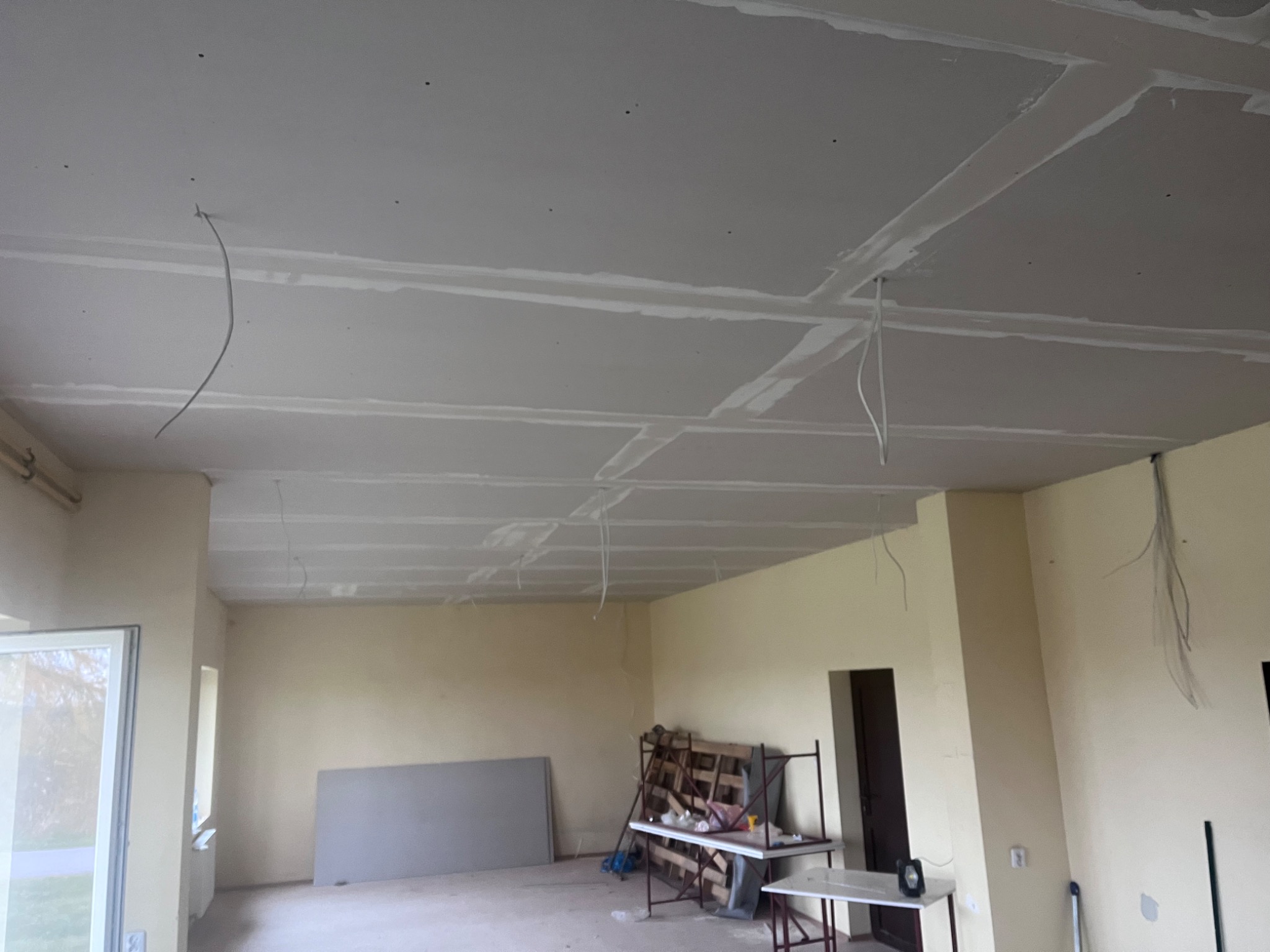 Wnętrze w Kielcach z widocznym sufitem z płyt kartonowo-gipsowych, przygotowanym do szpachlowania i malowania, z wystającymi przewodami elektrycznymi.